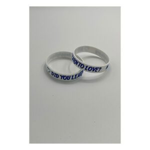 Two white bracelets with blue lettering on a table.